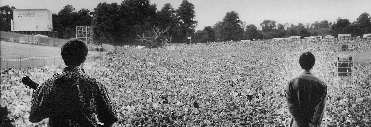 Black and White picture of Liam and Noel Gallagher on stage in front of a crowd